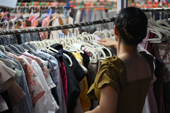 Shopper browsing a rack of secondhand clothing