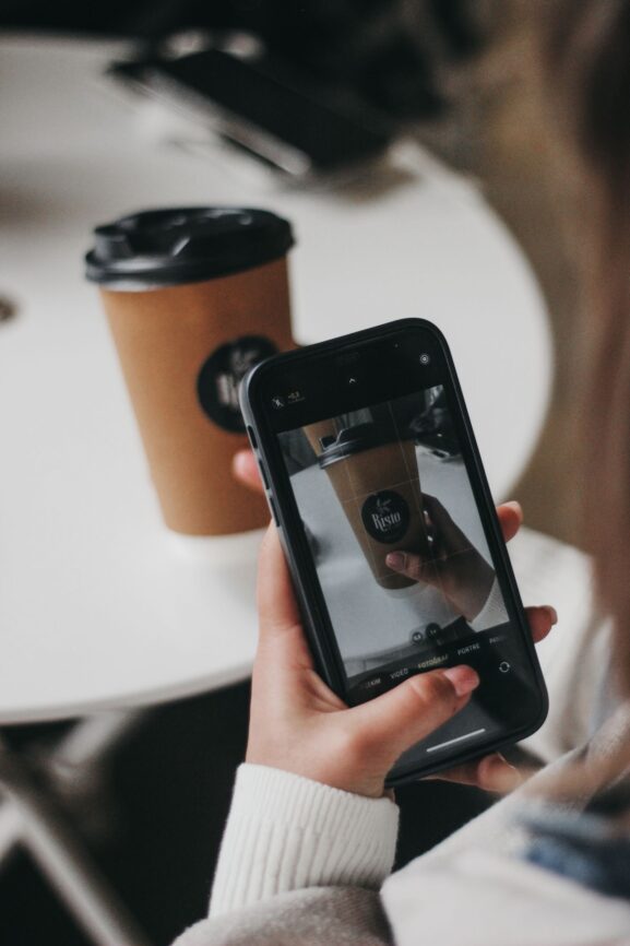 A hand holding a smartphone taking a photo of an item for an online listing