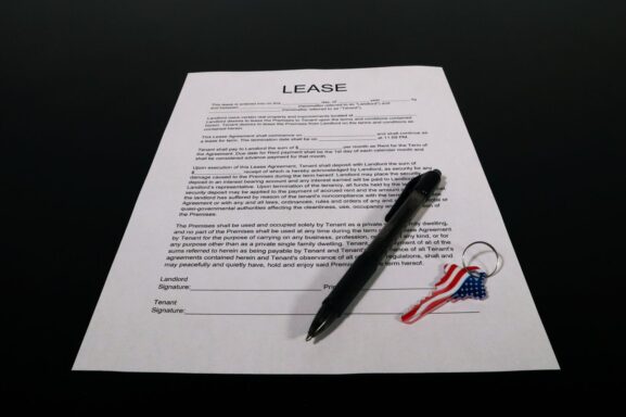 A lease agreement document with a pen and keychain, representing the moment a landlord and tenant finalize a rental contract