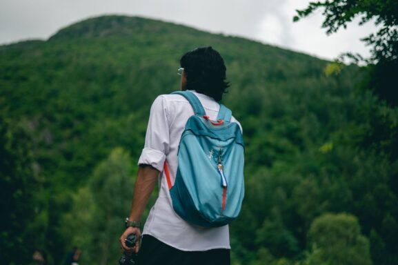 A hiker wearing a backpack walking along a trail on a hillside