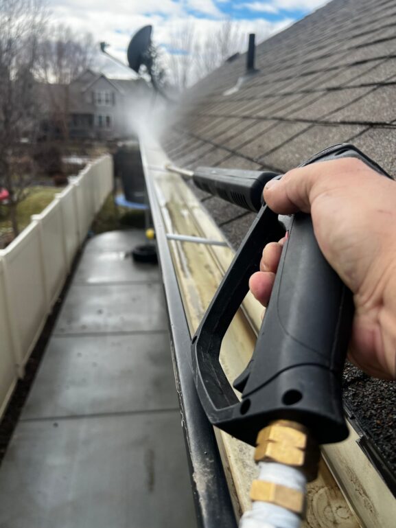 A professional cleaning residential gutters, one of several local services to book before winter arrives