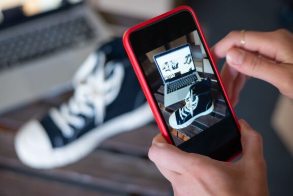 Seller using a smartphone to photograph a pair of sneakers for a local marketplace listing
