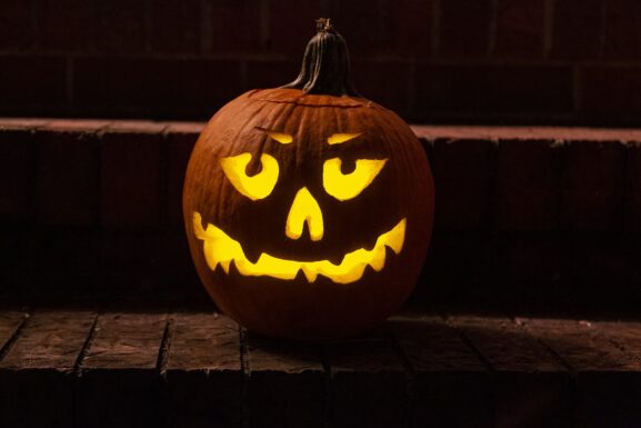 Carved jack-o'-lantern glowing orange on a porch step at night