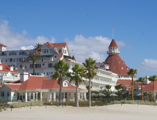 Hotel del Coronado red-roofed turret and white Victorian wings behind palm trees in Coronado, California