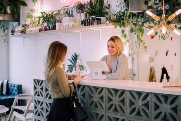 A customer paying at the counter of a small plant-filled local shop