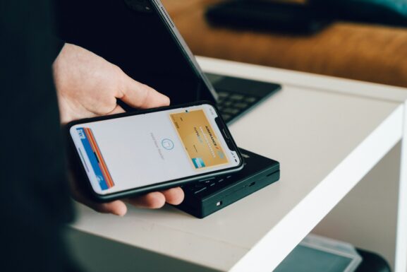 A person holding a smartphone over a card reader to make a contactless payment