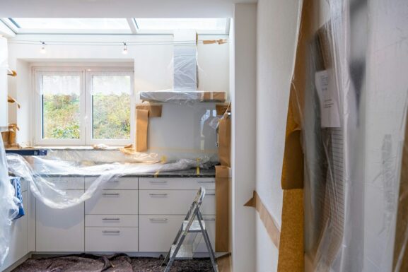 A kitchen under renovation with cabinets covered in protective plastic